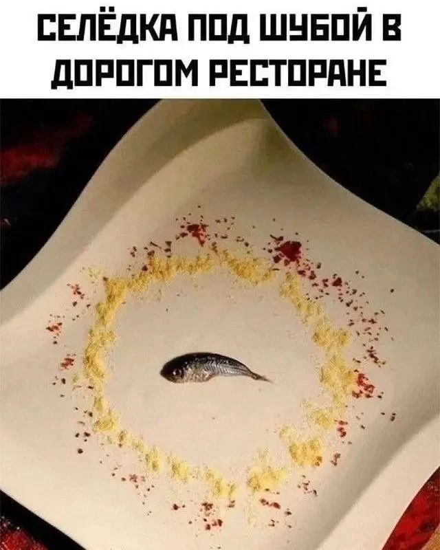 Селёдка под шубой в дорогом ресторане. На большой белой тарелке лежит маленькая рыбка, вокруг которой рассыпаны желтые и красные специи.