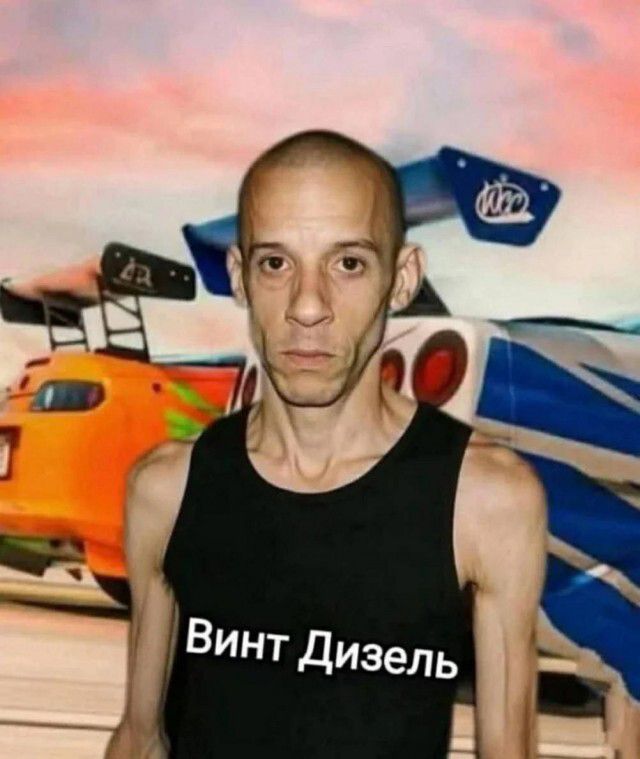 На изображении очень худой лысый мужчина в черной майке на фоне тюнингованных спортивных автомобилей. На майке надпись: 'Винт Дизель'.