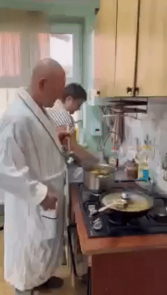 Мужчина готовит на кухне в халате