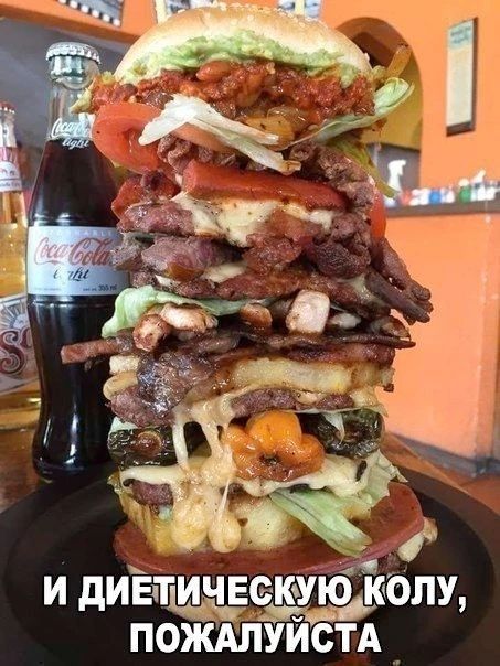 И ДИЕТИЧЕСКУЮ КОЛУ, ПОЖАЛУЙСТА. Огромный многослойный бургер с мясом, сыром и овощами, рядом бутылка Coca-Cola light.