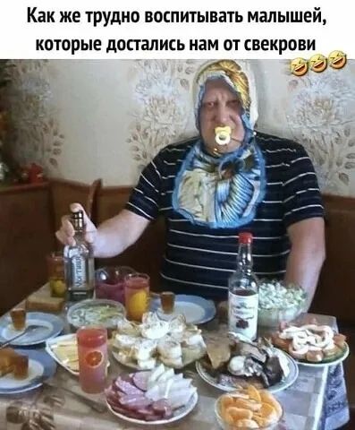 Как же трудно воспитывать малышей, которые достались нам от свекрови. Мужчина в образе младенца с соской и слюнявчиком сидит за столом с алкоголем и закусками, держа в руке бутылку водки.