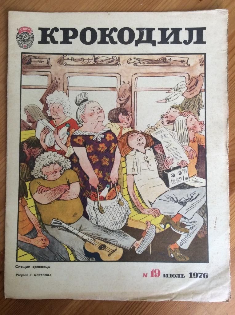 КРОКОДИЛ СССР Спящие красавцы Рисунок А. ЦВЕТКОВА № 19 ИЮЛЬ 1976. Обложка журнала «Крокодил» с иллюстрацией, изображающей переполненный общественный транспорт, где множество людей спят или выглядят крайне уставшими, некоторые в нелепых позах. Среди них женщина с авоськой, мужчина с гитарой, другой с радиоприемником. Подпись к рисунку: «Спящие