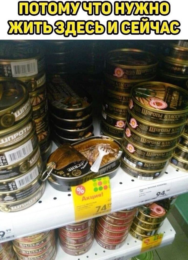 ПОТОМУ ЧТО НУЖНО ЖИТЬ ЗДЕСЬ И СЕЙЧАС. На полке магазина среди банок шпрот одна банка открыта, внутри рыба и маленькая пластиковая вилка. Рядом ценник 'Акция! 74.99'.
