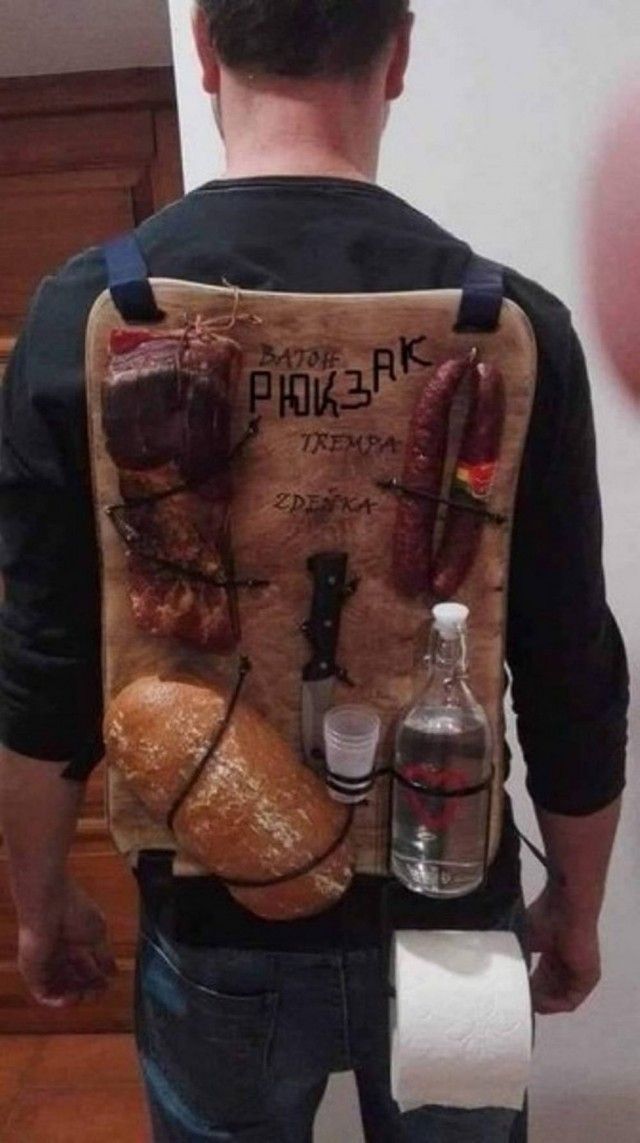 BATOH РЮКЗАК TREMPA ZDEŇKA. На спине у человека прикреплены: кусок мяса, колбасы, нож, батон хлеба, бутылка с прозрачной жидкостью, стаканчик и рулон туалетной бумаги.