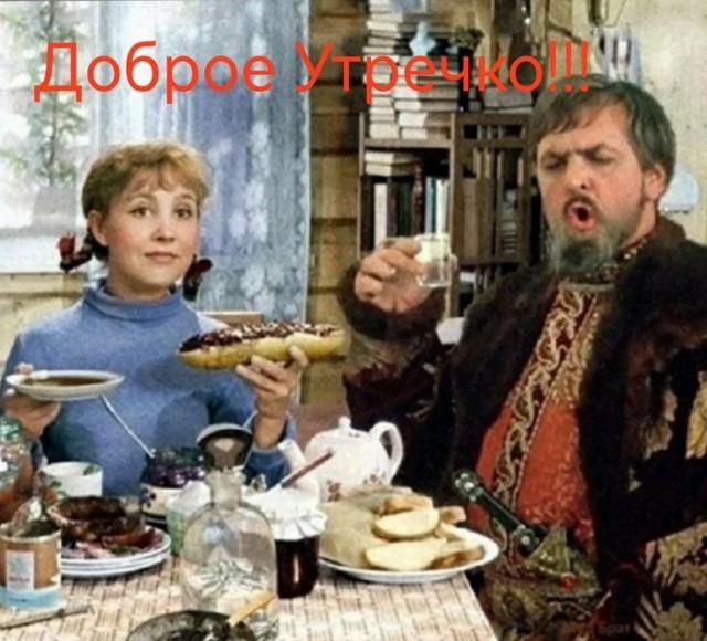 Доброе Утречко!!! Женщина улыбается, держа выпечку. Мужчина с бородой в историческом костюме держит рюмку и выглядит удивленным или недовольным.