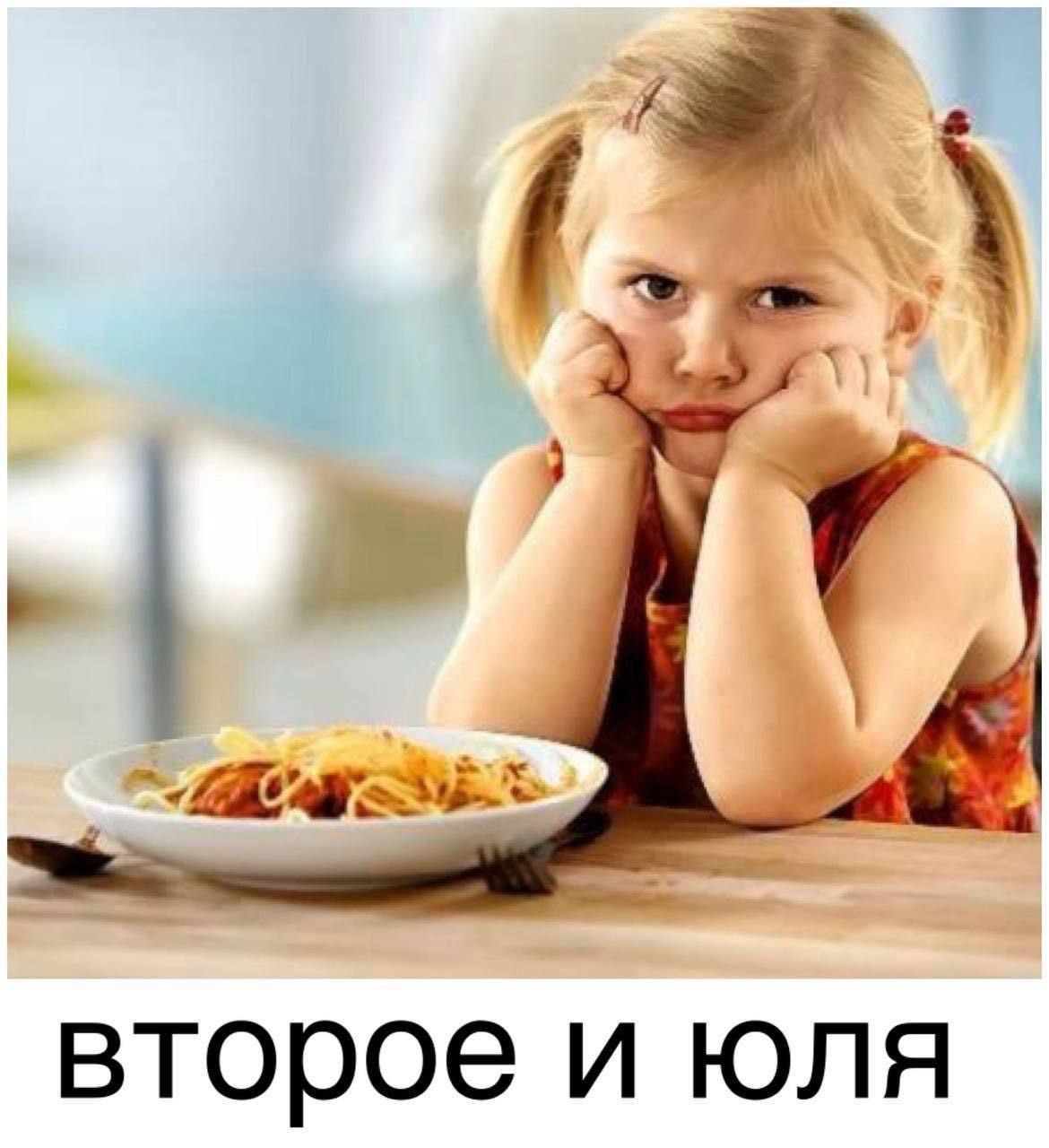второе и юля. Девочка сидит за столом перед тарелкой со спагетти, подперев щеки руками, и выглядит недовольной.