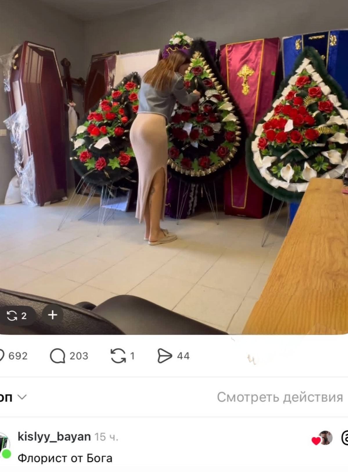 Флорист от Бога. Девушка в обтягивающей юбке занимается составлением траурного венка в помещении с гробами.