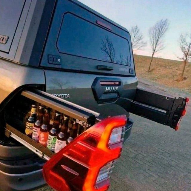 Автомобиль с выдвижной полкой в багажнике, заполненной бутылками пива.