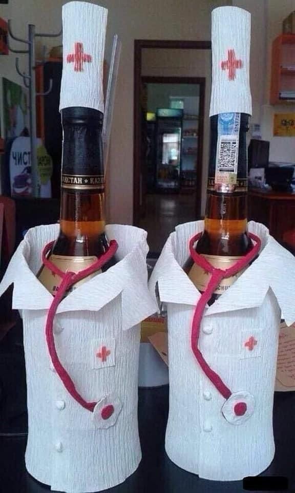 Две бутылки алкоголя одеты как врачи: белые халаты, шапочки и стетоскопы из бумаги.