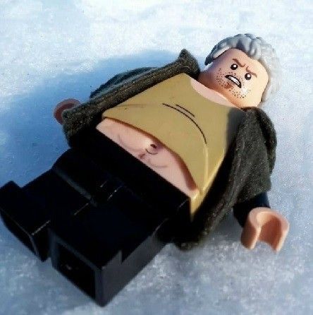 Лего-фигурка лежит на льду; частично обнажён торс.
