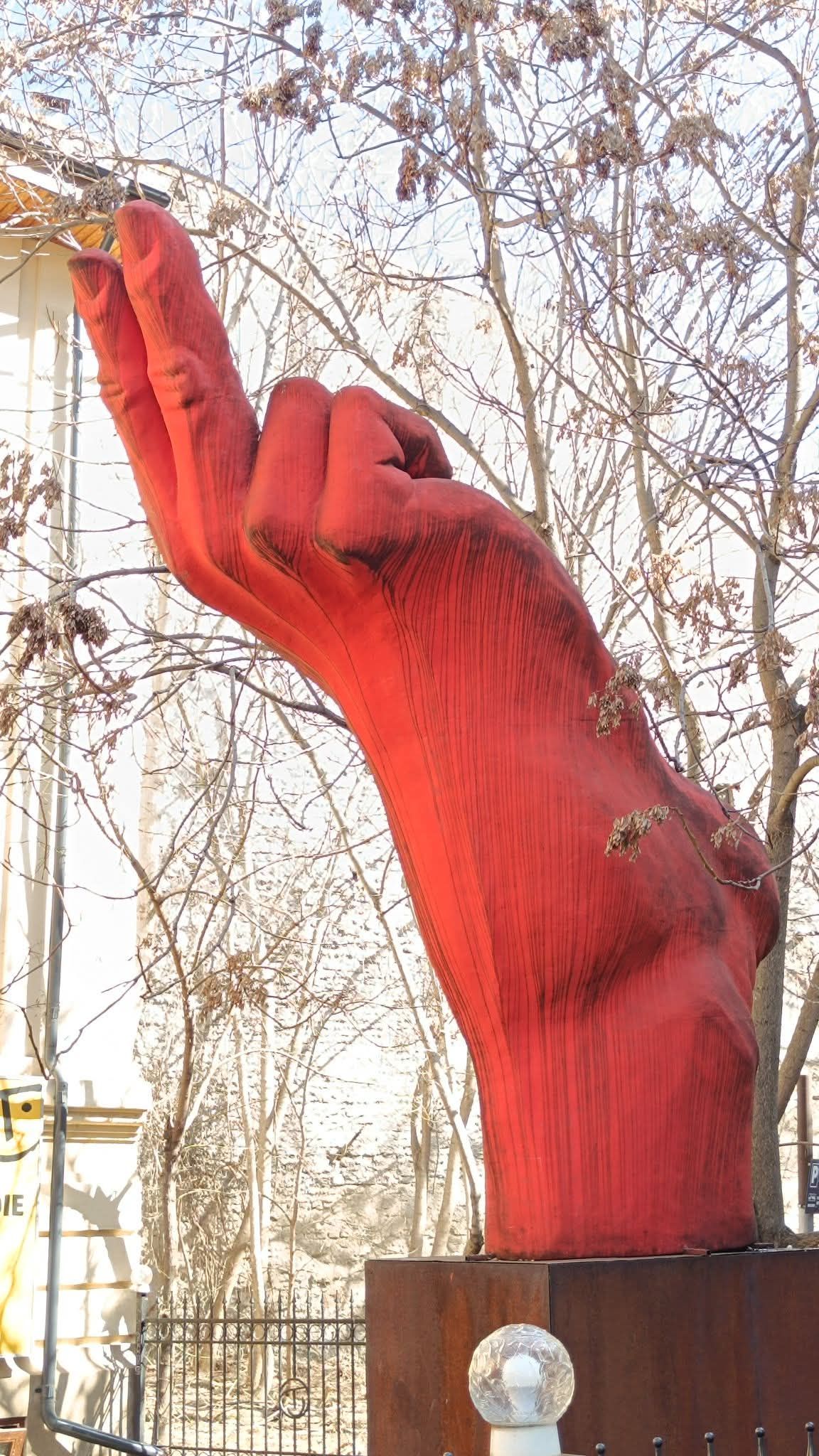Большая красная рука-скульптура на улице зимой