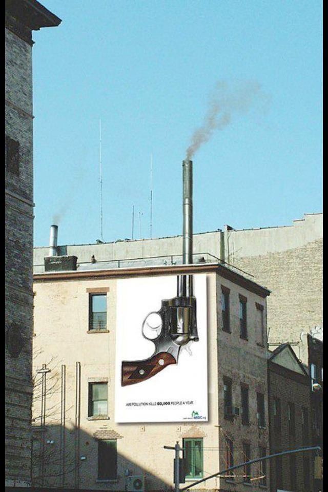 Улица с рекламной монтажной работой на стене: изображение пистолета на боковой стене здания и дымящий трубой сверху.