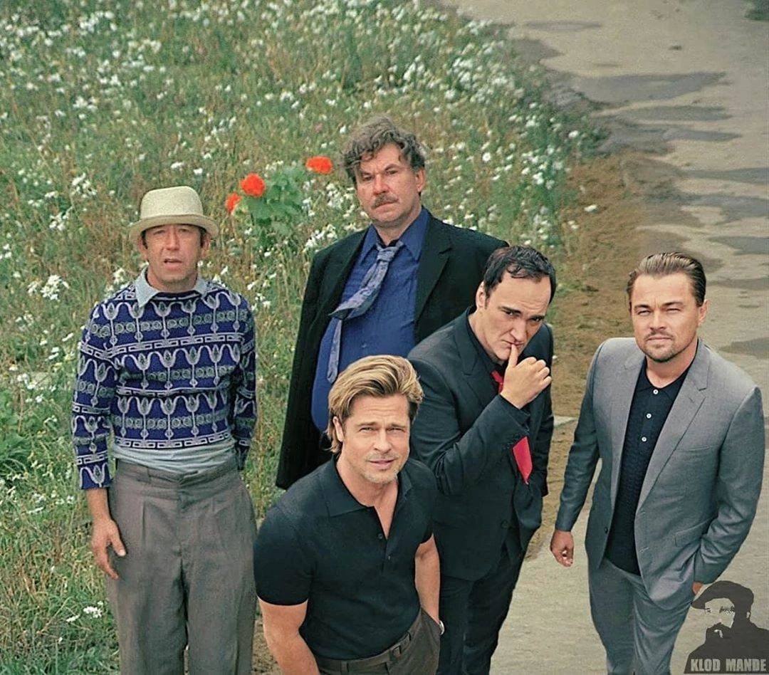 Группа мужчин позирует на улице среди цветов и травы.