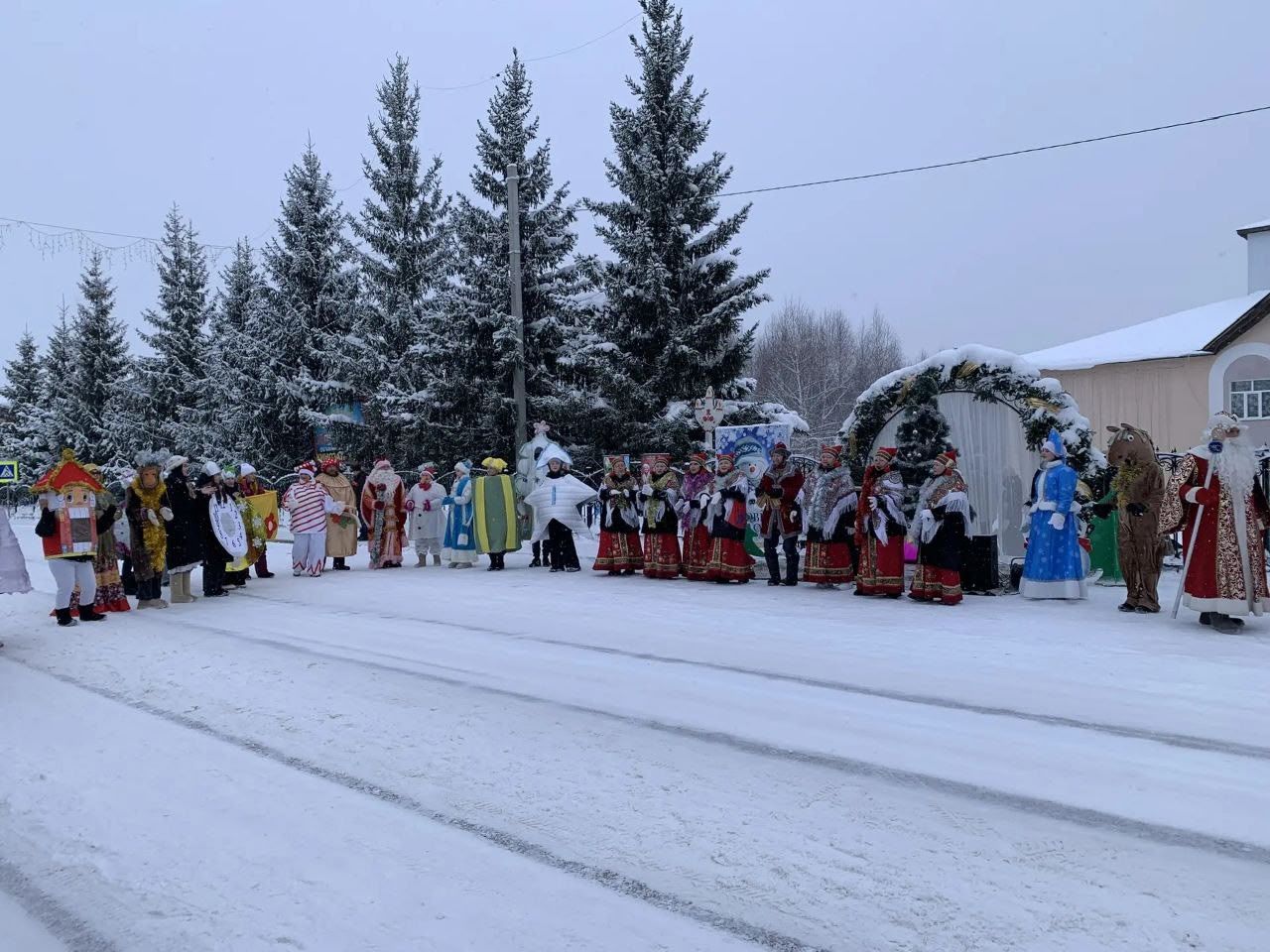 Хоровод людей в традиционных нарядах на снегу перед елкой