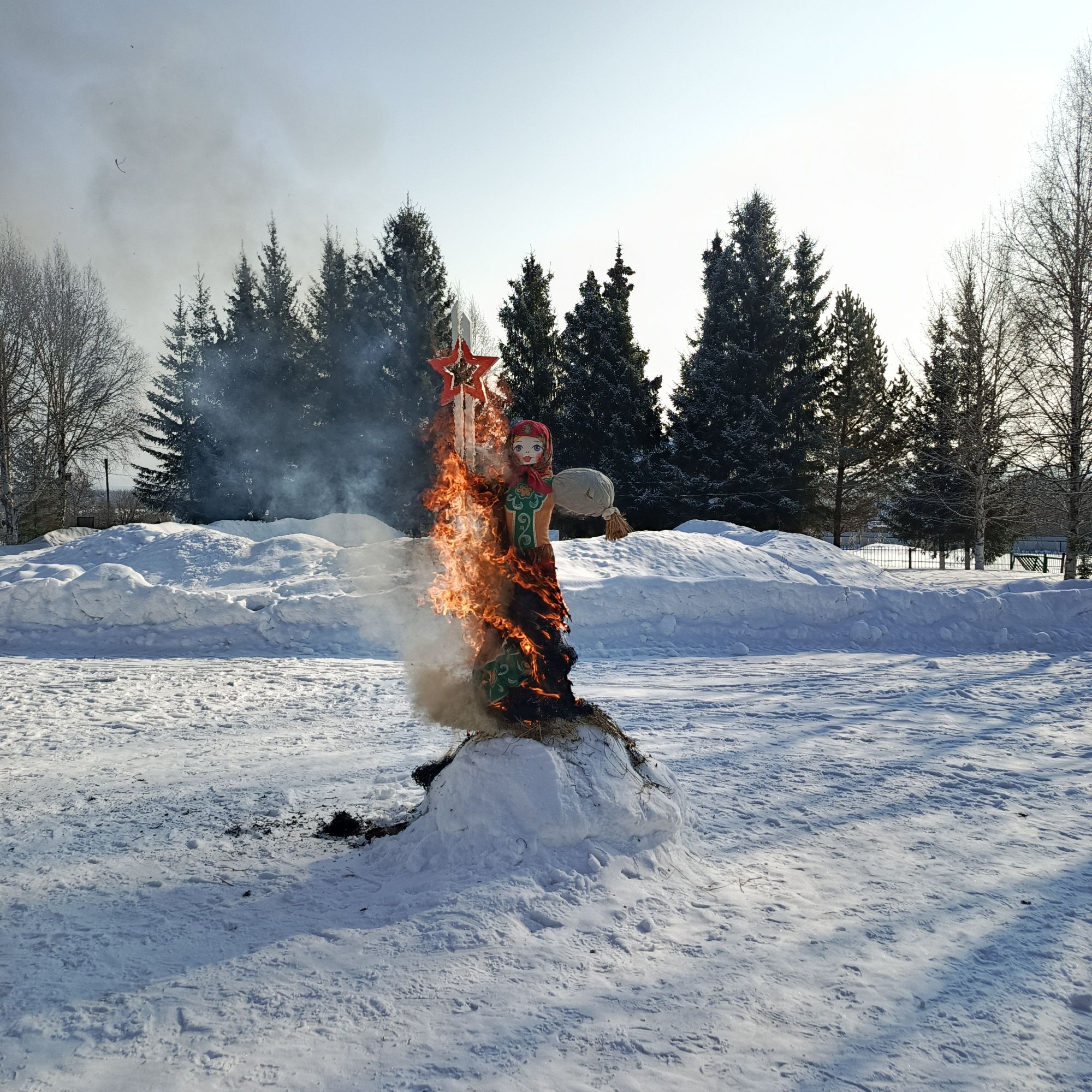 Зимний пейзаж: на снегу горят фигура/чучело, вокруг деревья