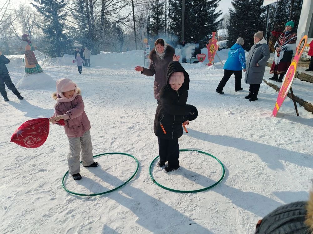 Дети играют на снегу в городке, прыгая в обручи на снегу