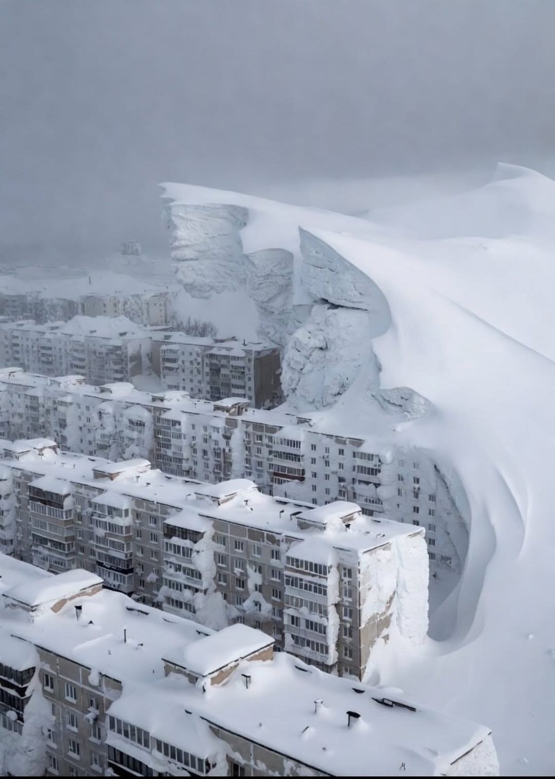 Снежная лавина обрушилась на городской квартал, накрывая высотки снегом.