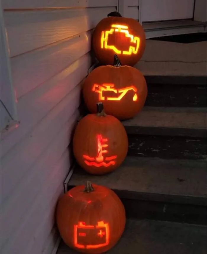 Несколько светящихся тыкв с пиксельными рисунками стоят на ступеньках возле дома.