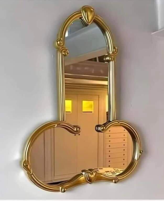 Золотое декоративное зеркало с выгнутыми рамами, образующими форму, напоминающую сердце.