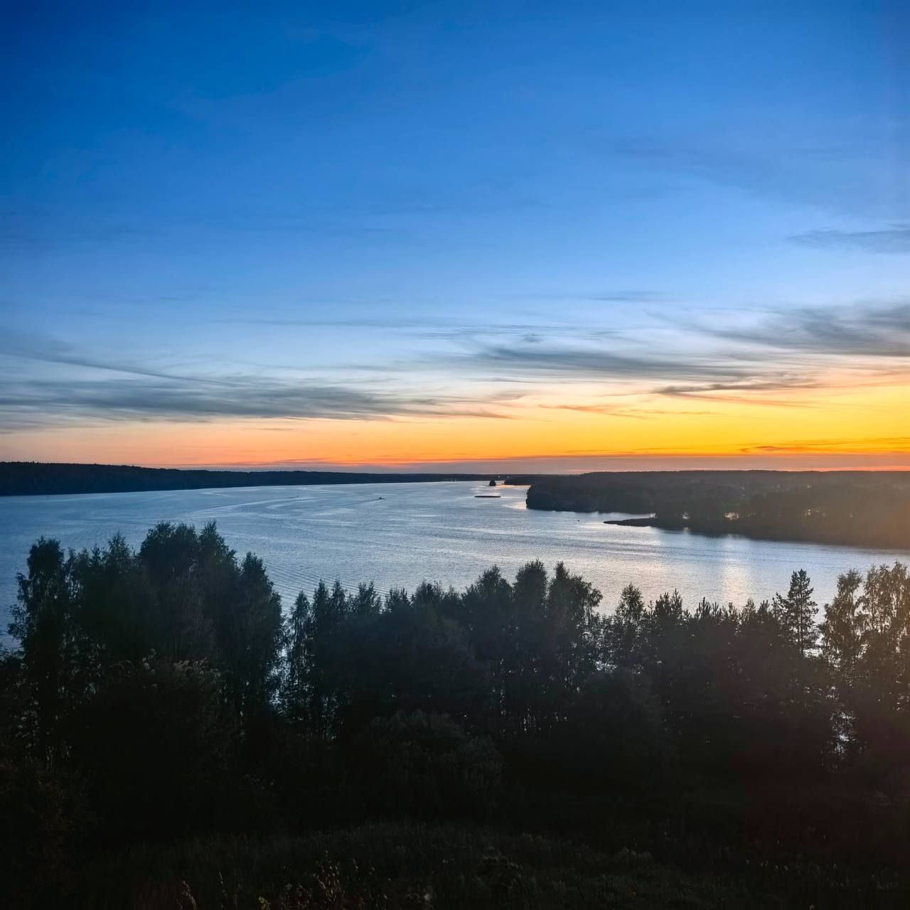 Закат над водной гладью и силуэты деревьев на берегу