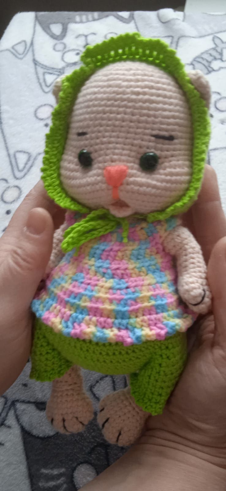 Вязаная крючком игрушка-зайчик в зелёной шапочке и ярком платье.