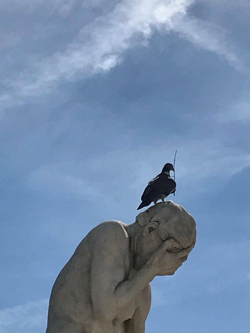 Скульптурная фигура думающего человека с птицей на голове сверху.