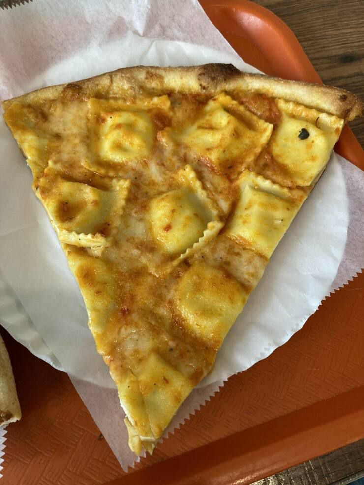 Кусочек пиццы с равиоли сверху на тарелке