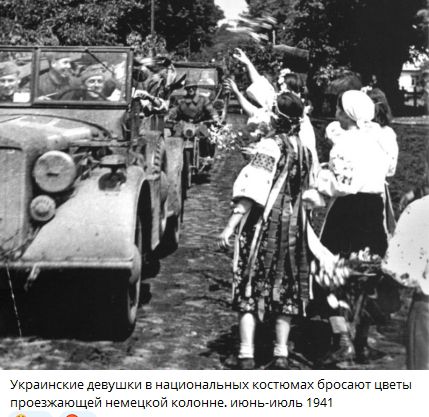 Украинские девушки в национальных костюмах бросают цветы проезжающей немецкой колонне. июнь-июль 1941