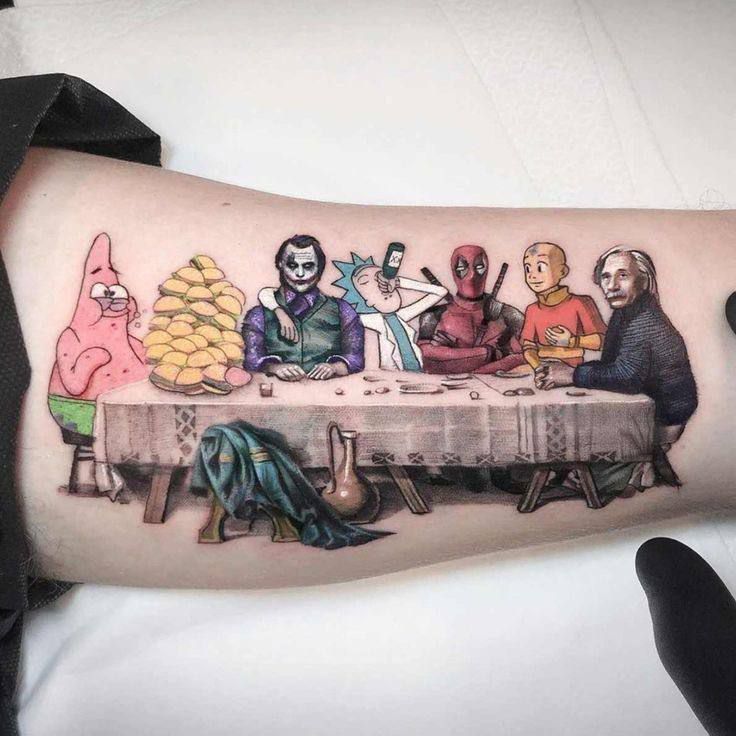 Татуировка на предплечье: за столом сидят фигуры в масках и необычных костюмах.