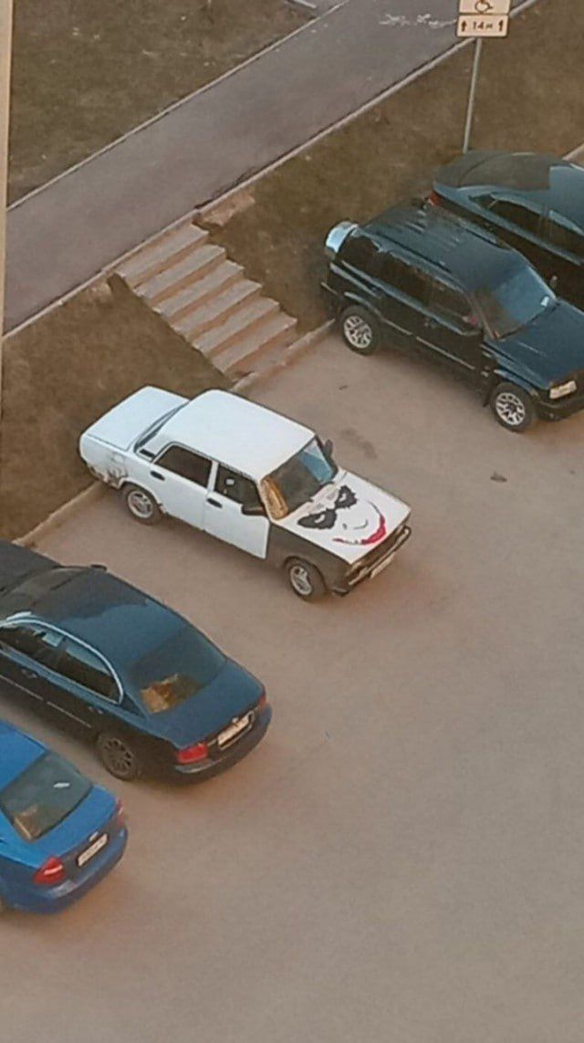 Белый пикап на парковке, на капоте нарисован рисунок животного (панда).