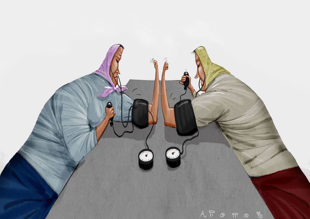 Два человека в худи сидят за столом и держат устройства с проводами; между ними колонки/микрофоны и наушники.