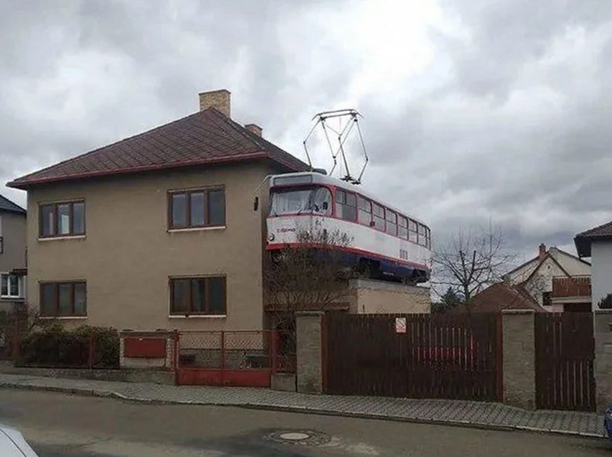 Трамвай застрял на крыше дома над двором, необычная сцена с висящим над домами трамвайным вагоном.