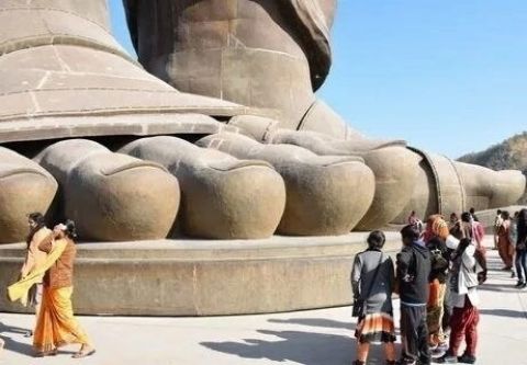 Гигантская каменная стопа statue и люди-туристы вокруг.