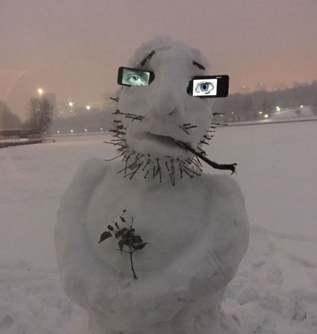 Снежный человек с очками и трубкой на заснеженном поле