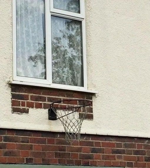 уличный баскетбольный обод на кирпичной стене под окном