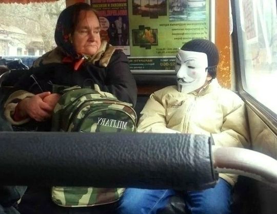 Старушка на автобусе рядом с человеком в маске Дя Фокса (V) за стеклом