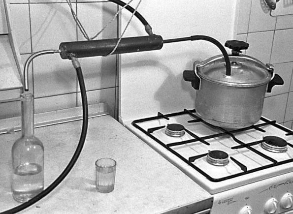 Кухонная перегонная установка: кастрюля на плите connected через трубку к бутылке.