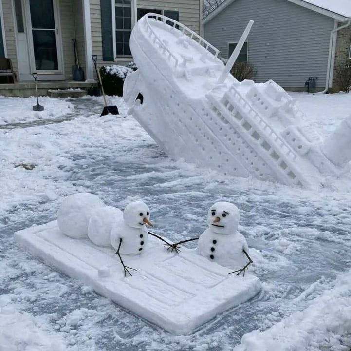 Большой снежный корабль-складна и две маленькие снеговики на снегу во дворе.