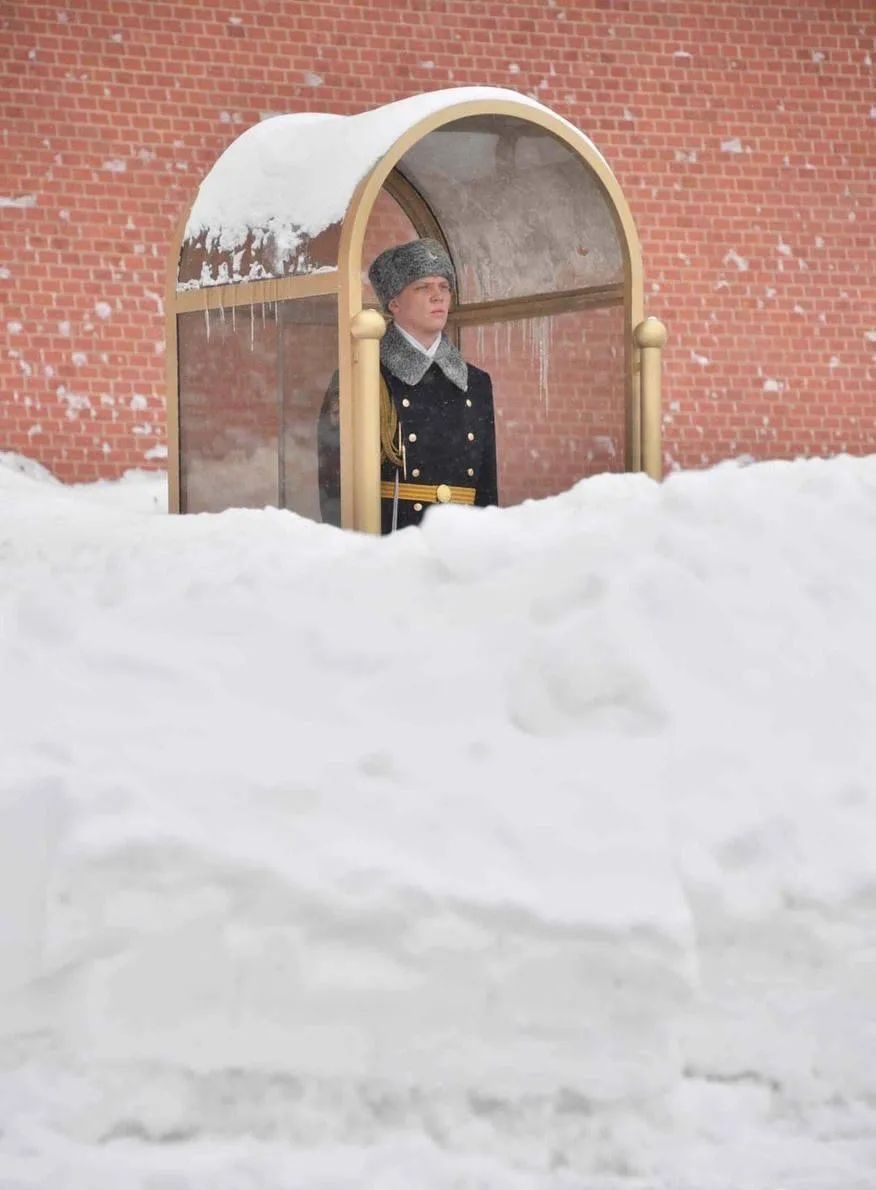 Военный в зимнем снаряжении стоит у будки в снегу