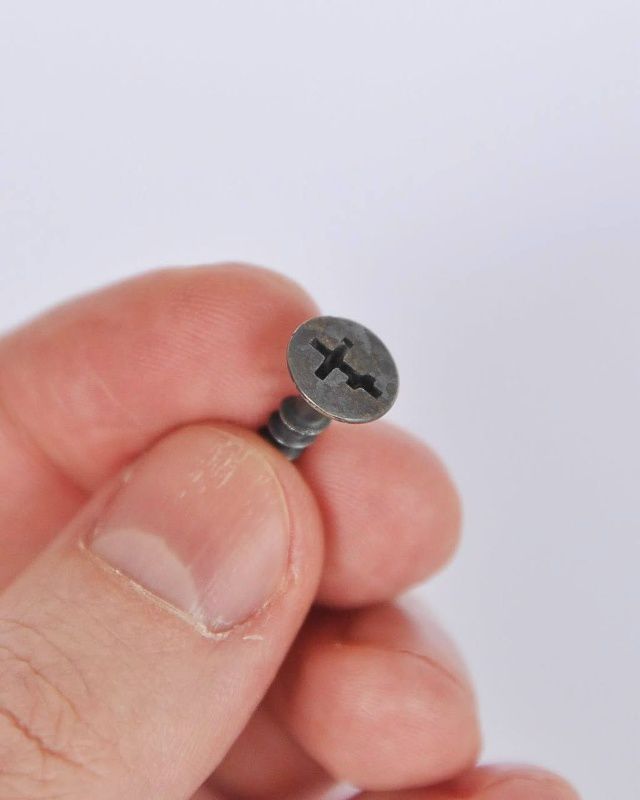 Маленькая винтовая шуруп в пальцах, крупный план