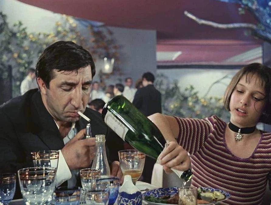 Мужчина прикуривает сигарету, девочка наливает напиток из бутылки.