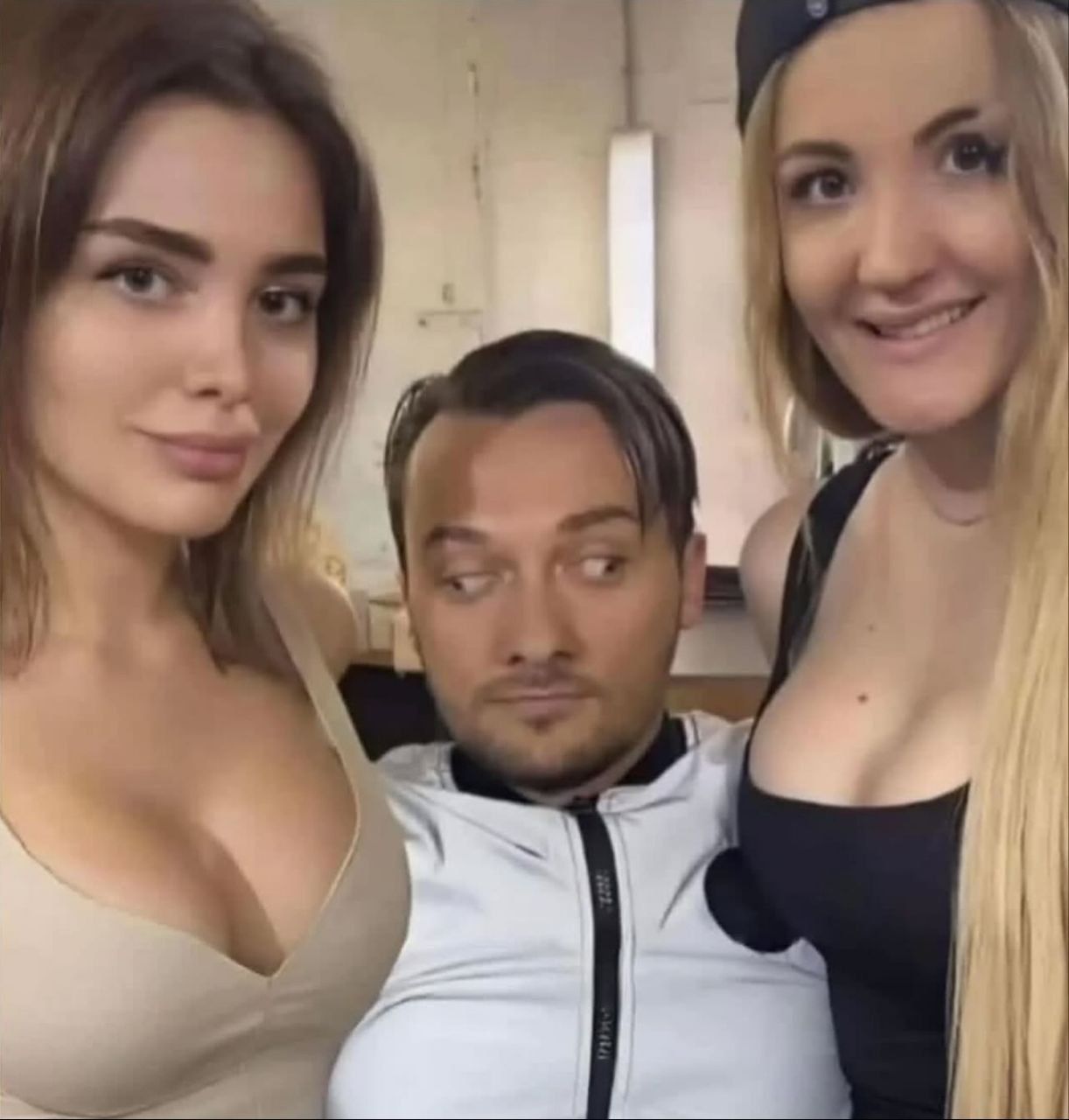 Три человека: мужчина посередине и две девушки слева и справа, в студийной обстановке.