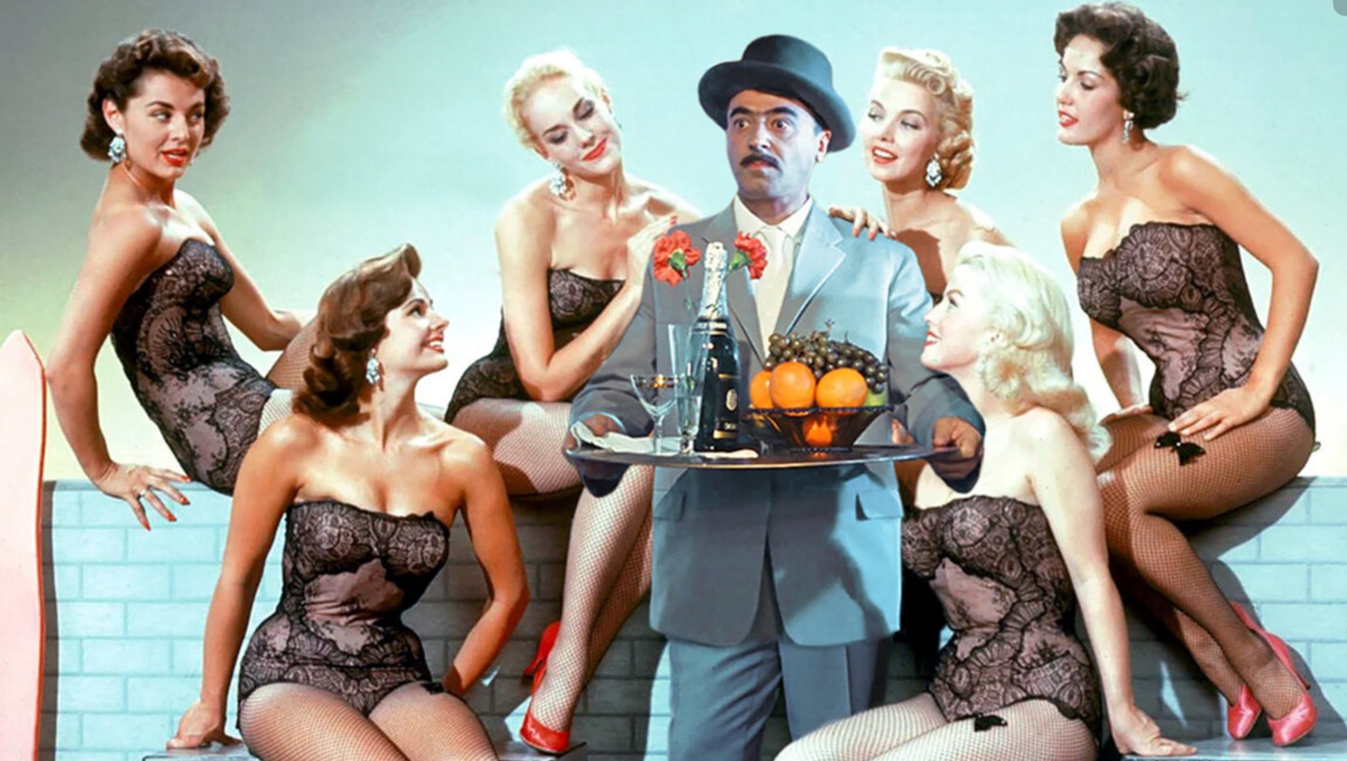 мужчина в костюме среди женщин в корсетах на фотосессии