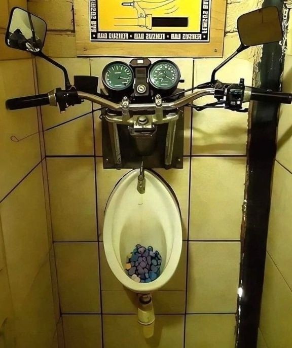 Монеты лежат в чаше унитаза/писсуара под рулевой панелью мотоцикла.