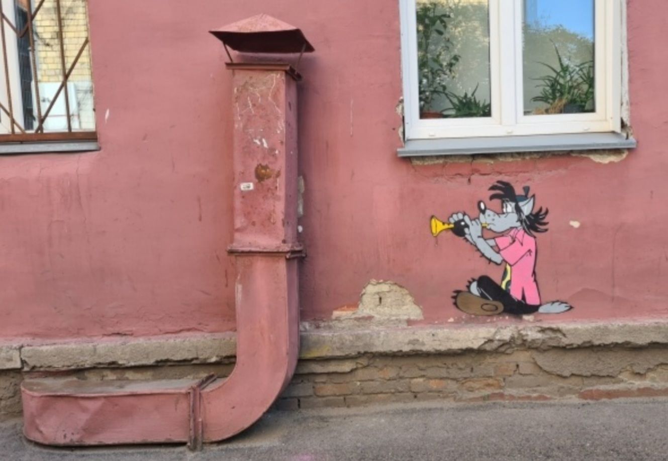 Граффити на розовой стене возле окна: женщина с рупором и труба на фоне стены.