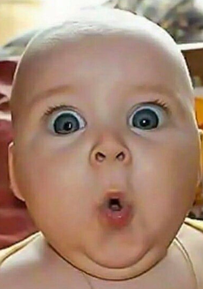 Младенец с удивленным выражением лица и широко раскрытыми глазами.