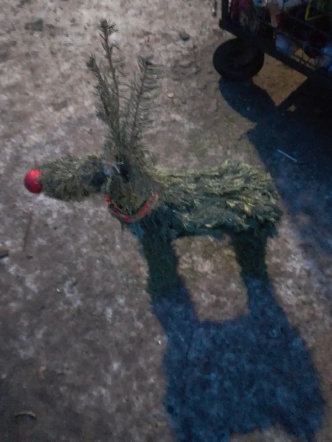 Декоративная фигура животного из веток на улице, напоминающая лошадку/олень с красным носом.