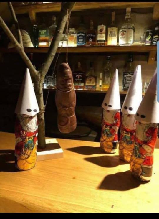 Фигурки в белых конусных колпачках на столе, рядом с бутылками на полке