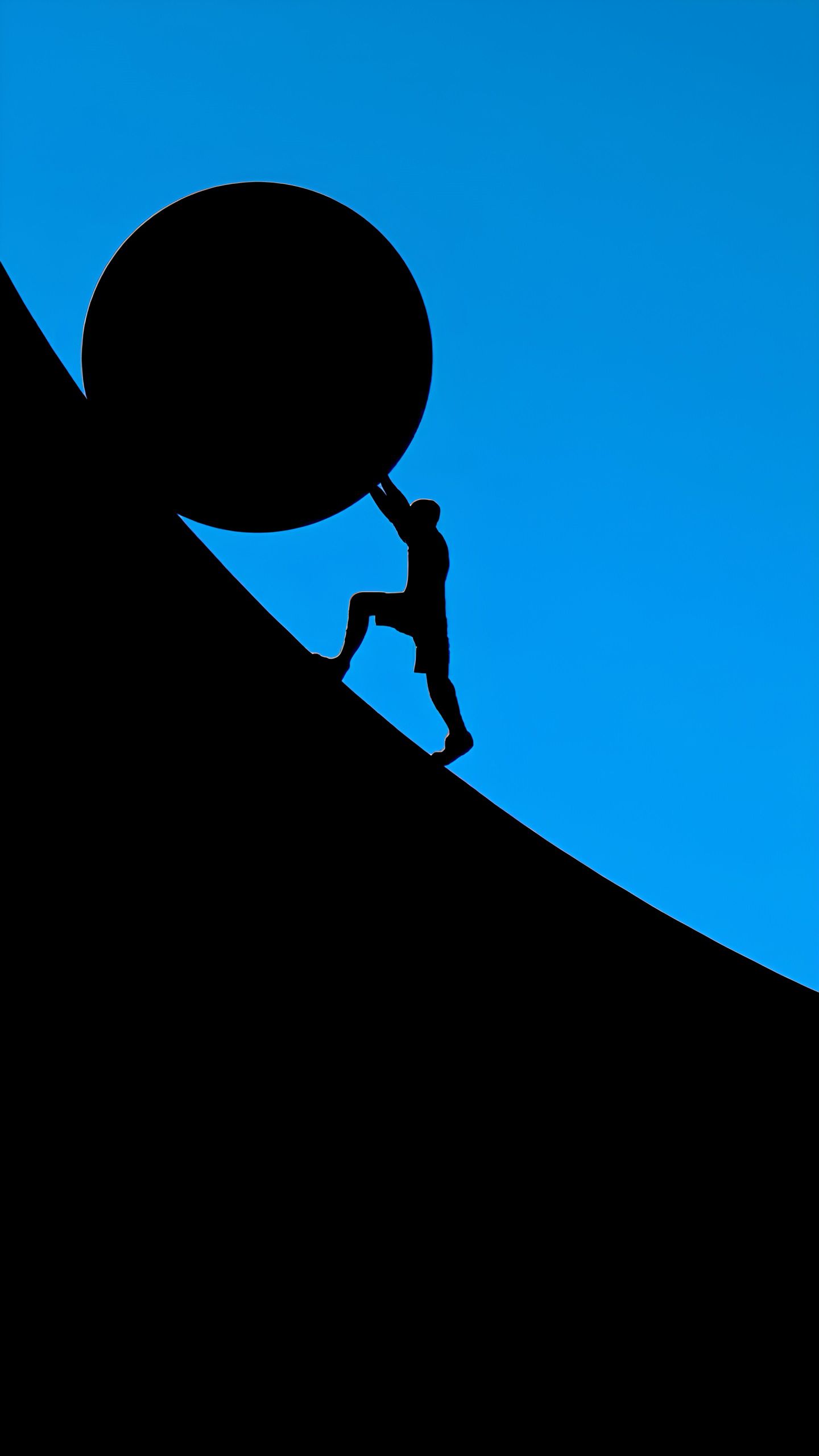 Силуэт человека толкает гигантский шар на склоне.