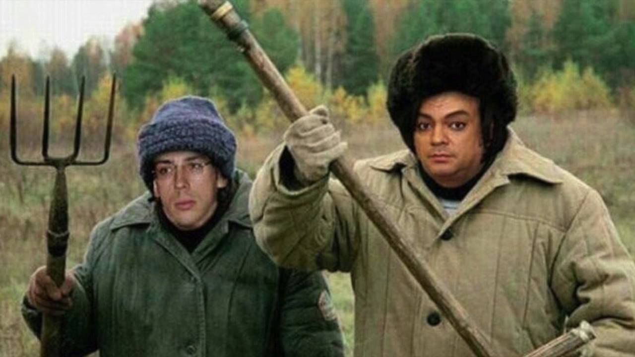 Два мужчины в зимних куртках держат вилы на открытом поле.